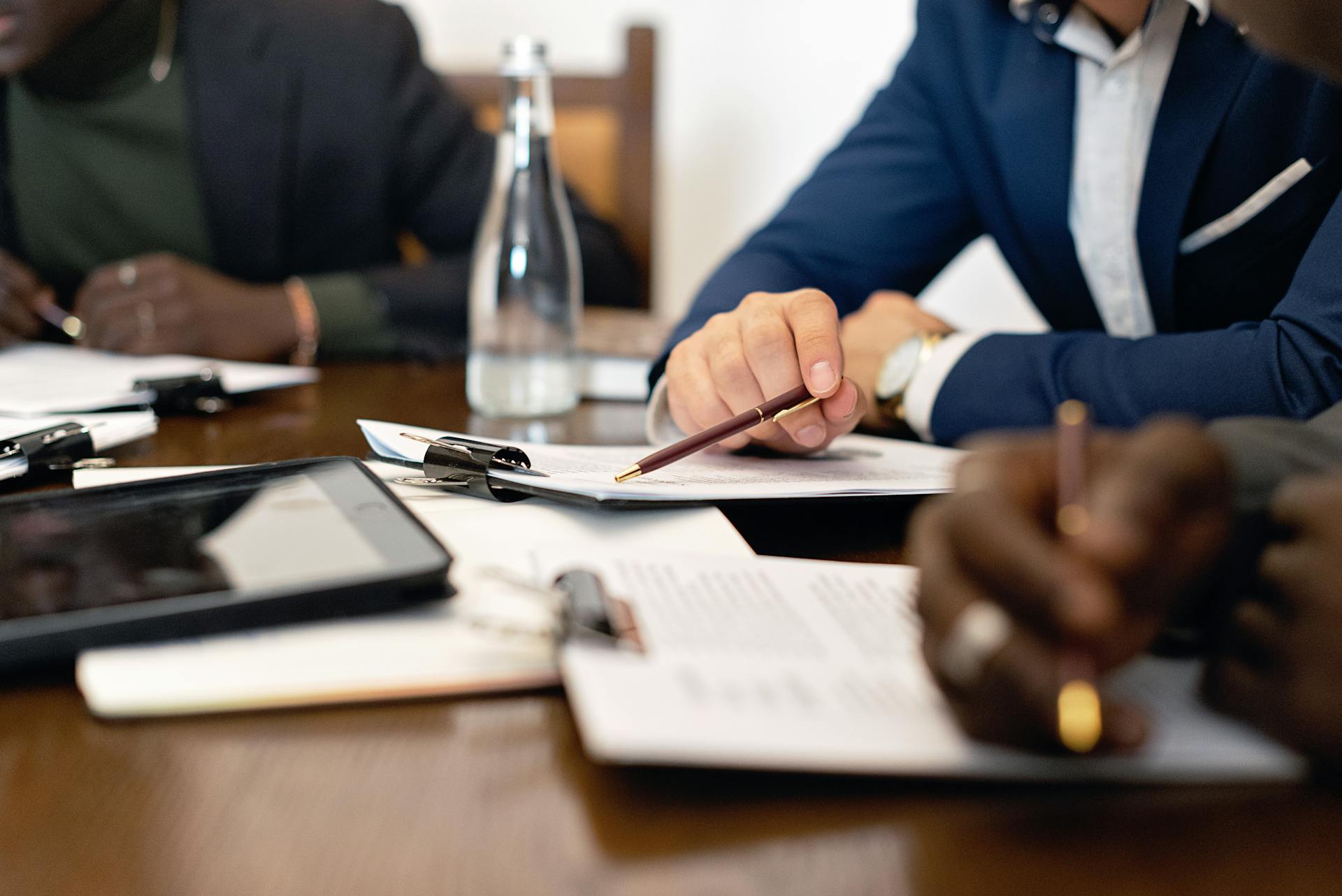 Business meeting with adults discussing and signing contracts over a table.