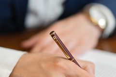 Close-up of a hand signing a business contract with a fountain pen.