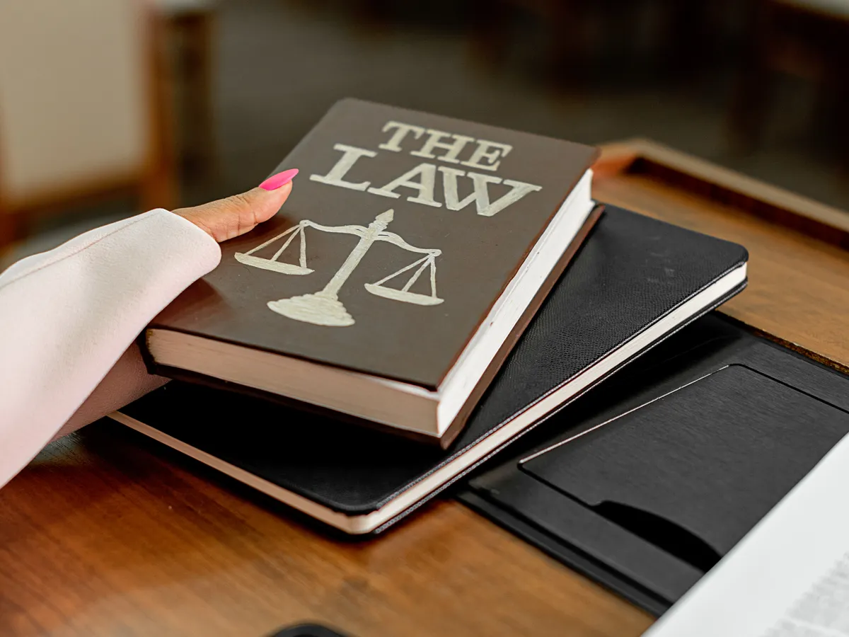 A hand placing a book titled 'The Law' on a table, representing the legal expertise of lawyers in Supreme Court Delhi.