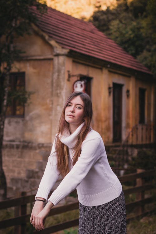 Young woman in sweater standing near house