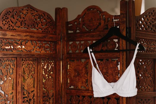 A white bra hanging on a decorative wooden screen, showcasing intricate carvings.