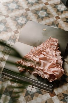Elegant pink lingerie displayed on a geometric patterned book, creating a soft and artistic composition.