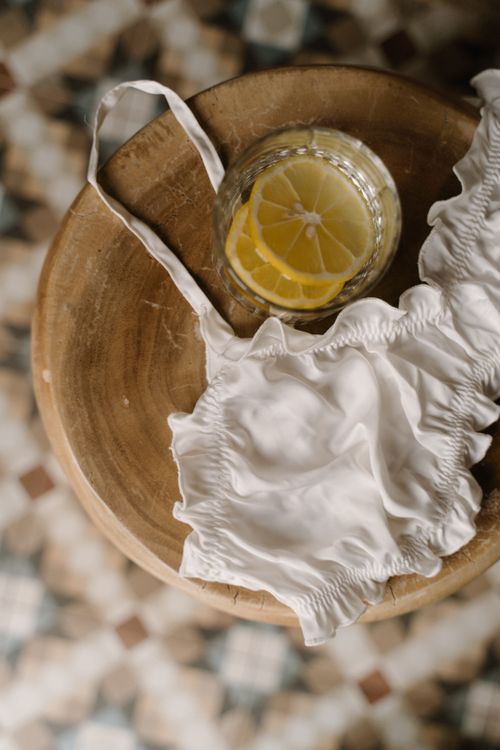 Free Silk lingerie draped on a table beside a glass with lemon slices. Stock Photo