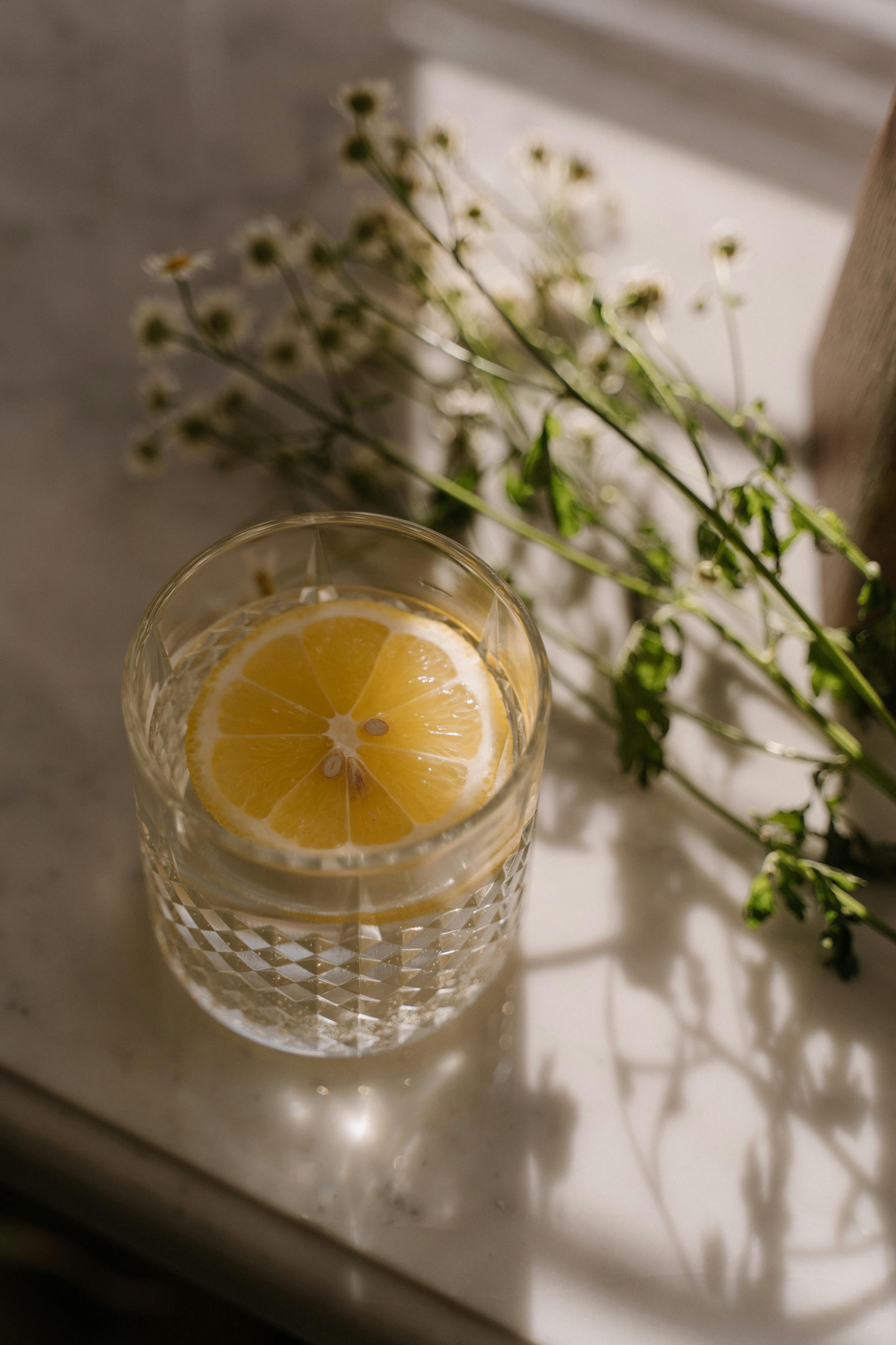 Elegant drink with lemon slice in crystal glass on marble, soft light.