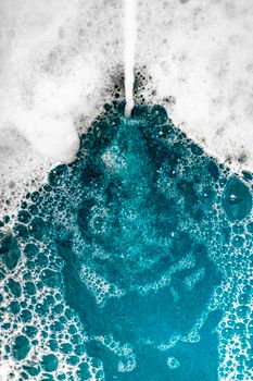Close-up of blue foam bubbles merging with water, creating a mesmerizing texture.