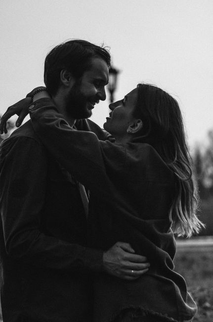 Black and white photo of a couple embracing outdoors, capturing tender affection.