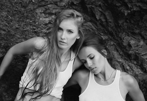 Free Artistic black and white portrait of two women posing against a rocky backdrop. Stock Photo
