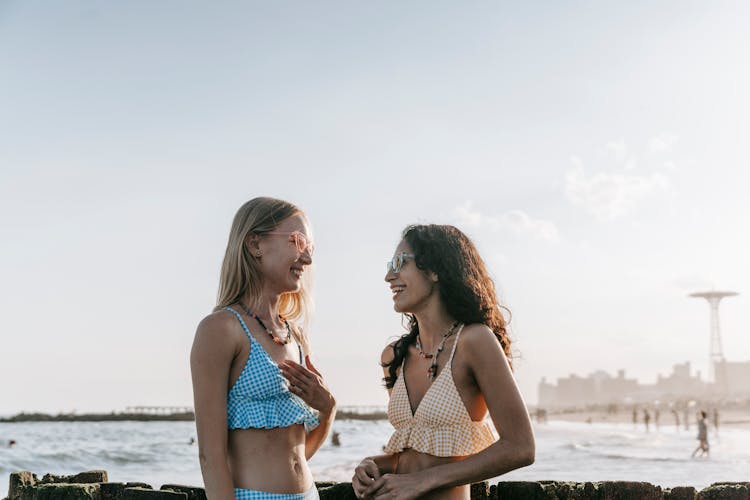 Smiling Girls In Swimsuits Talking On Beach