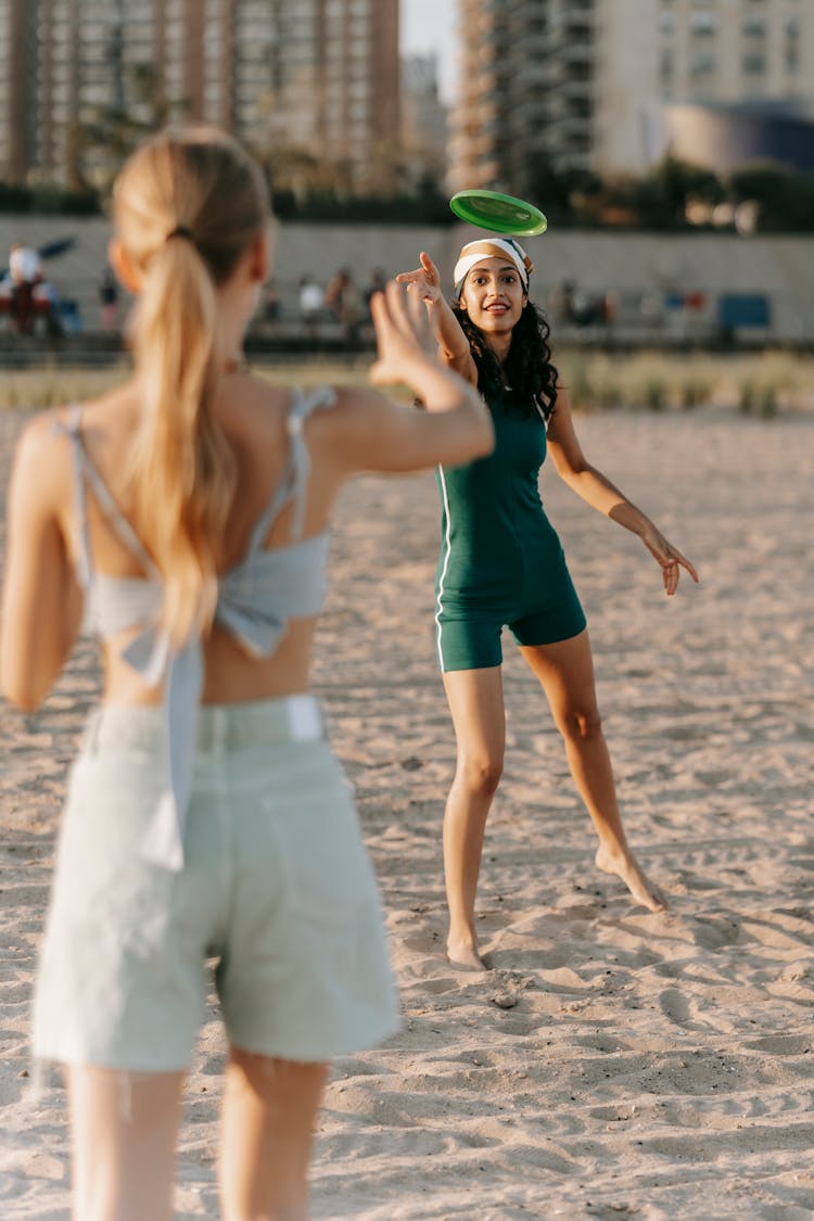 Women Playing With A Frisbee On A Beach