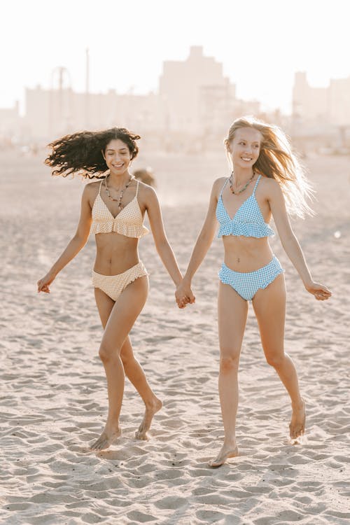 Young Women in Bikinis on the Beach Holding Hands 