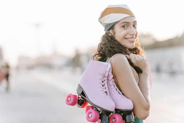 Selective Focus Photo Of A Woman Carrying Her Pink Roller Skates