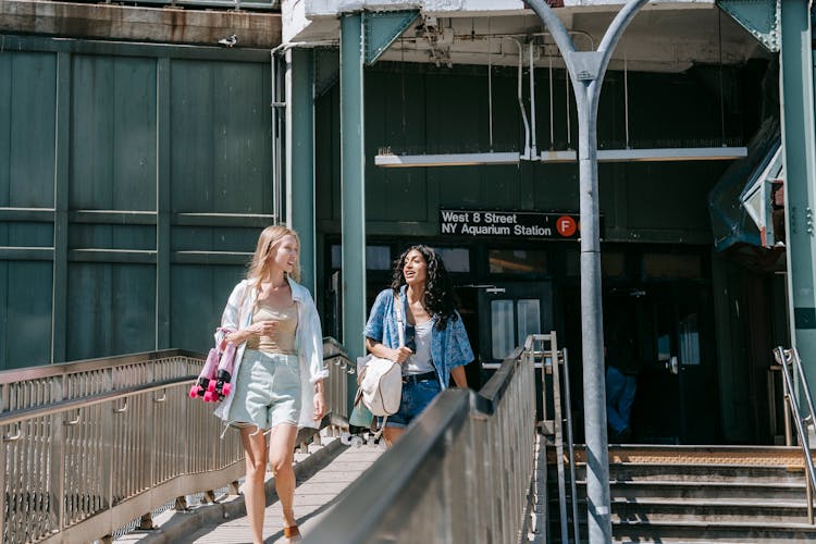 Young Women Holding Roller Skates While Walking Out Of A Subway Station 