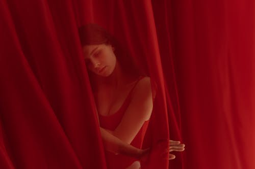 A Woman Wearing a Bodysuit behind a Red Curtain