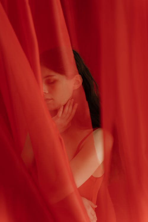 A Woman Wearing a Bodysuit behind a Red Curtain
