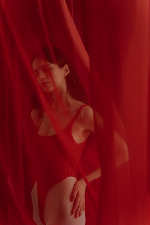 
A Woman Wearing a Bodysuit behind a Red Curtain