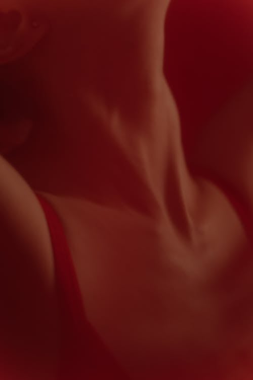 
A Woman Wearing a Tank Top behind a Red Curtain
