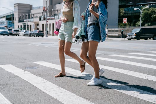 Two women in casual summer attire crossing an urban street.