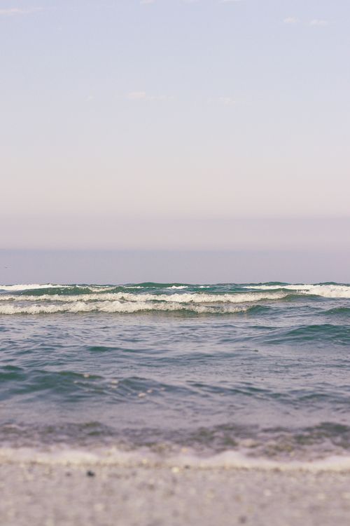 Free Gentle waves rolling onto a serene beach under a soft, calming sky. Stock Photo