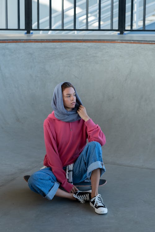 Free A Woman in a Hijab Sitting on Her Skateboard Stock Photo
