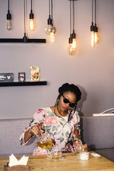 一位时髦的女人在一家舒适的咖啡馆里，在现代吊灯下倒茶