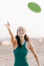 女人在海滩上享受一天，玩飞盘，在阳光下微笑