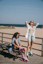 两名妇女在阳光明媚的海滩木板路上享受轮滑