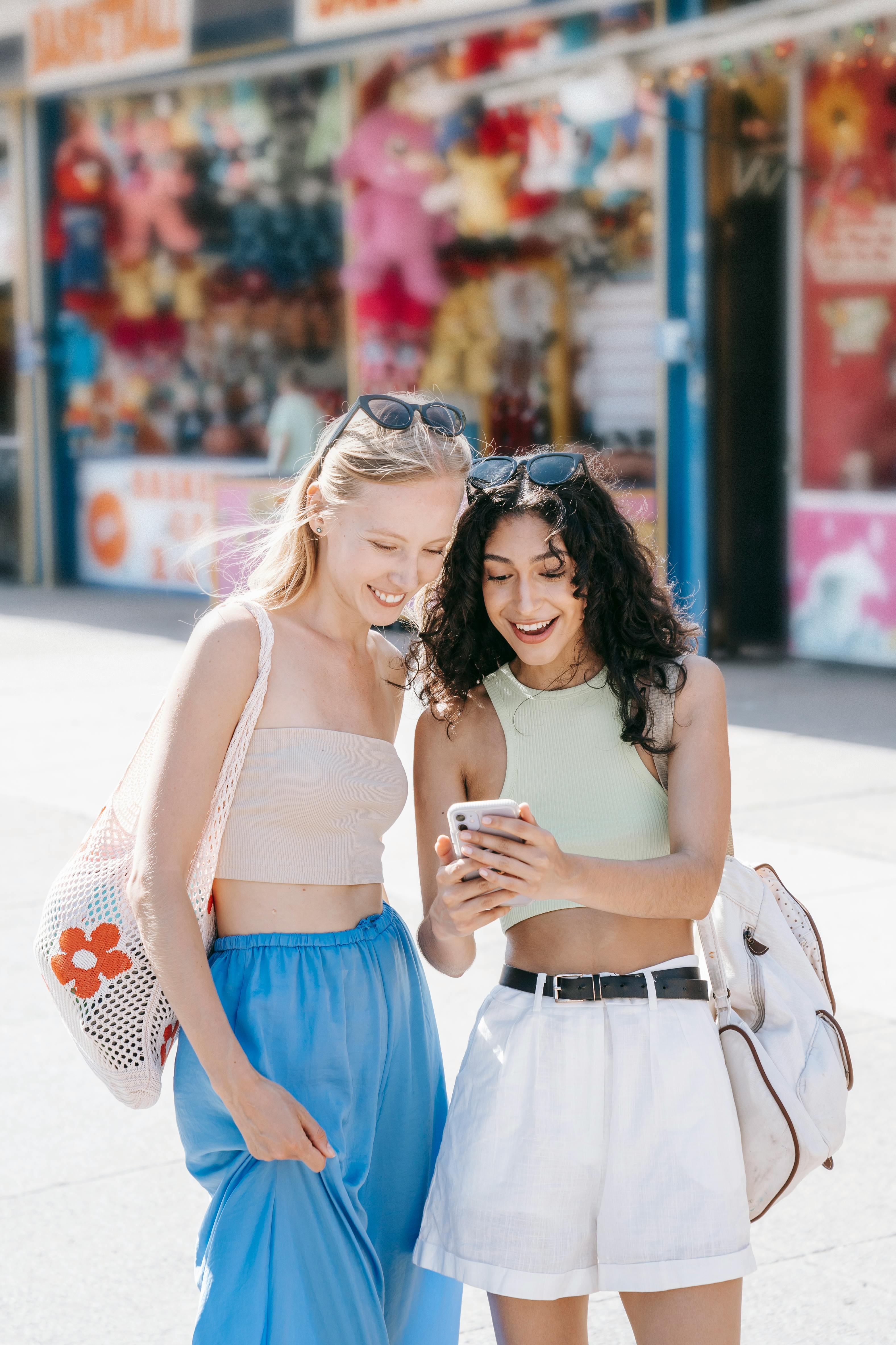 smiling girls using cellphone on street