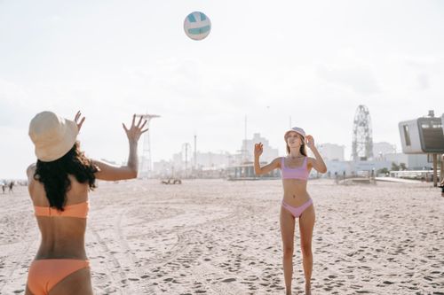 Free Two women enjoying a beach volleyball game under a clear sky. Stock Photo