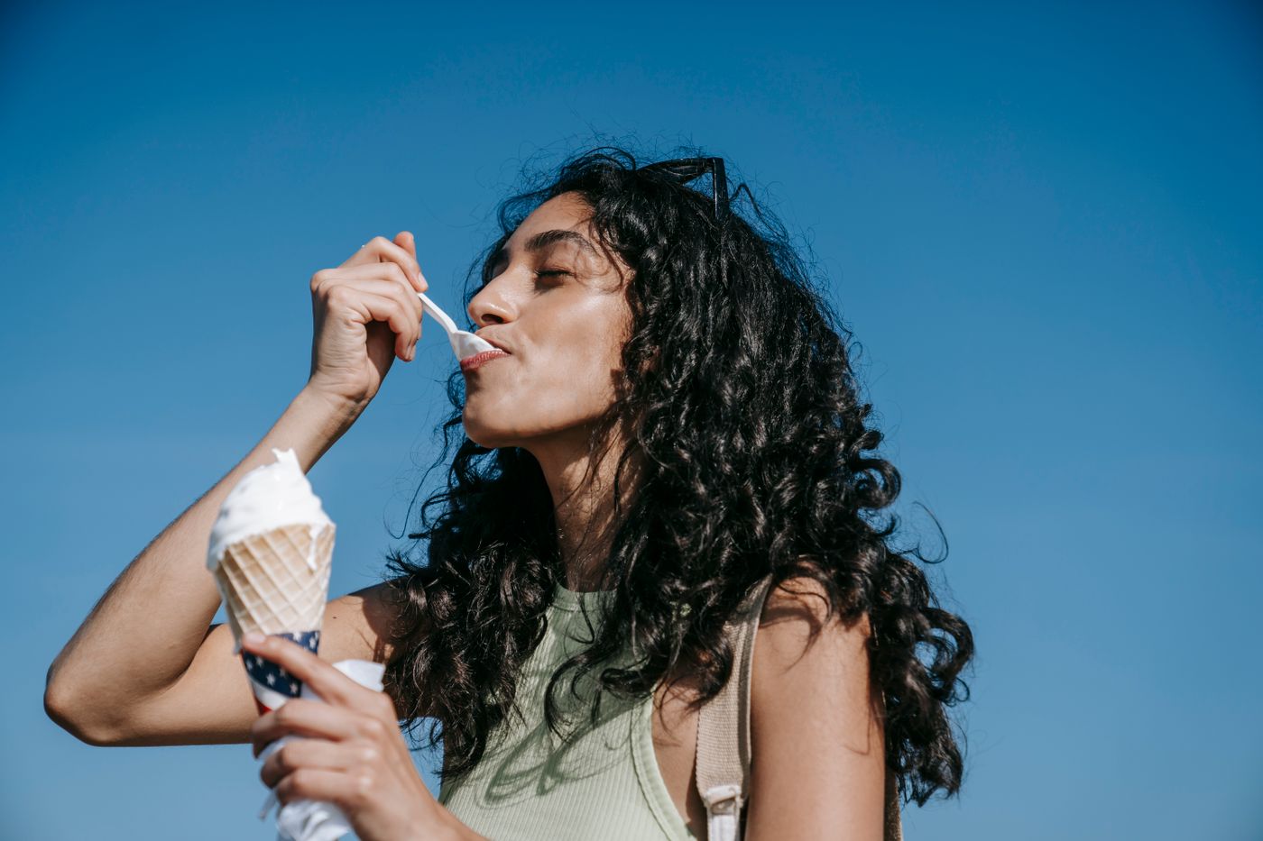 Woman eating an ice cream cone outdoors on a warm day