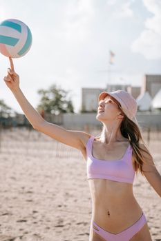 A young woman in swimwear playing volleyball on a sunny beach, embracing the summer vibe.