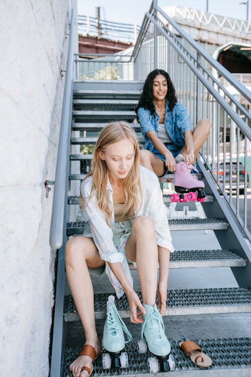 Women Wearing Roller Skates while Sitting on Metal Staircase