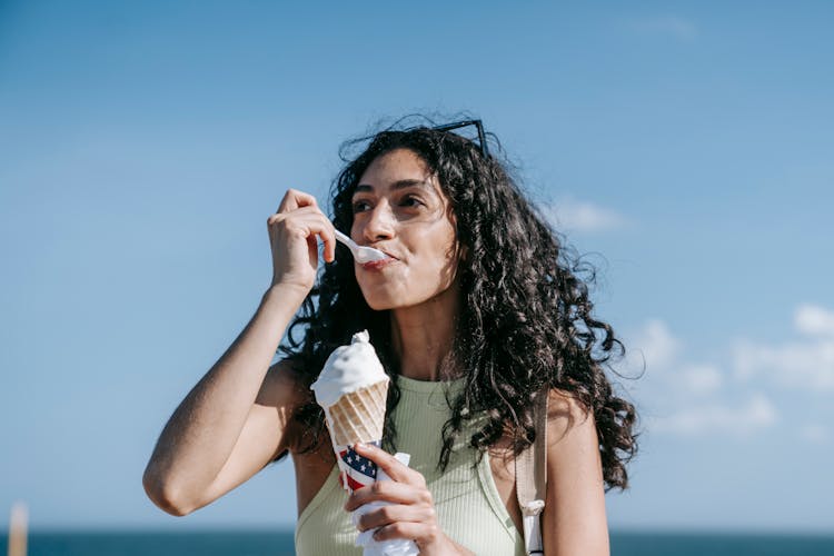 Woman Eating Ice Cream Against Blue Sky