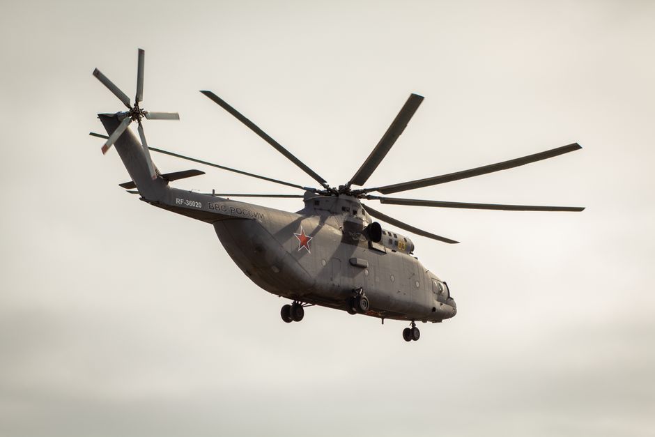 Low-angle view of a military helicopter in flight against a clear sky, showcasing its size and design.