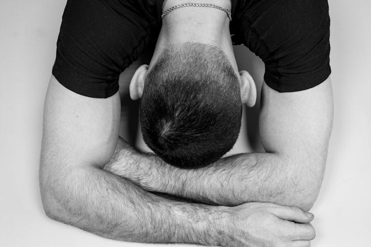 Grayscale Photo Of Man In Black T-shirt With Hairy Arms And Head Down