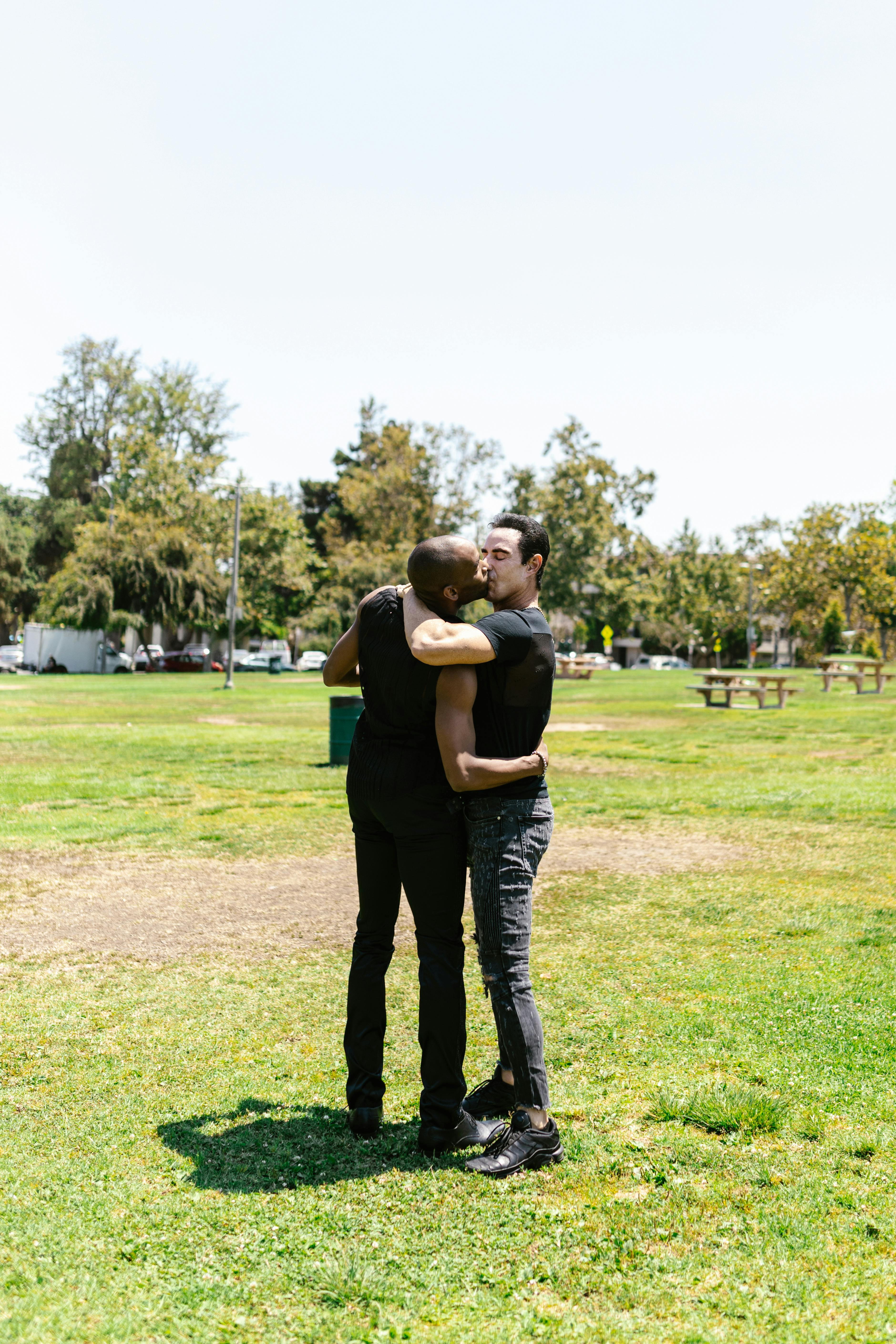 couple standing on grass field kissing