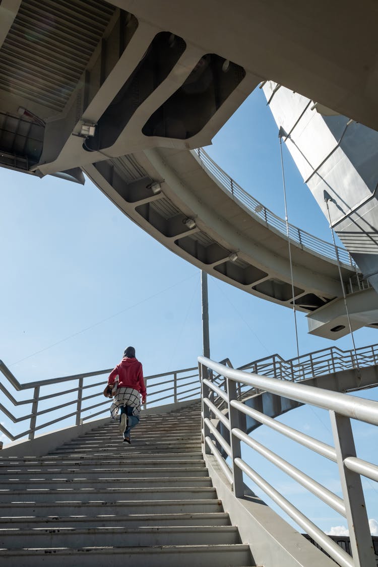 A Person Walking While Going Up On A Concrete Staircase