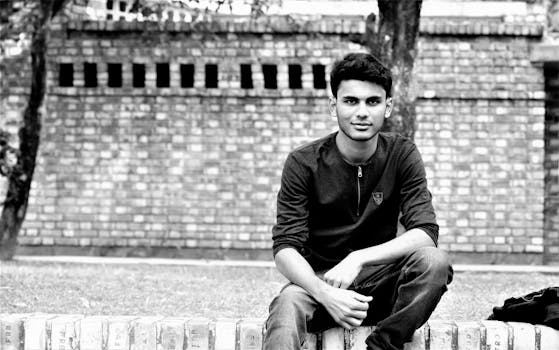 一张黑白肖像中，一名男子坐在户外，背靠砖墙