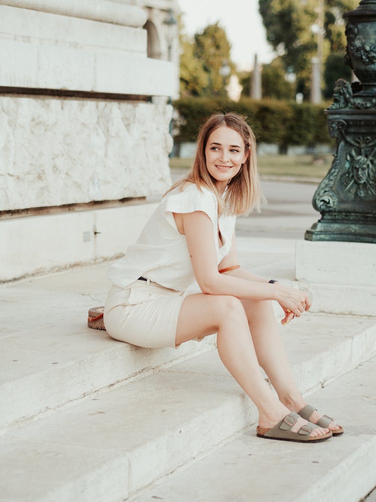 Smiling Woman Sitting On Stairs Near Old Building