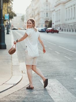 Happy woman crossing city street, enjoying a sunny day with a carefree smile.