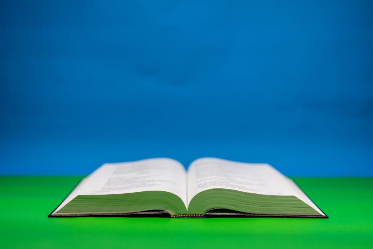 Close-Up Shot Of An Open Bible On A Green Surface