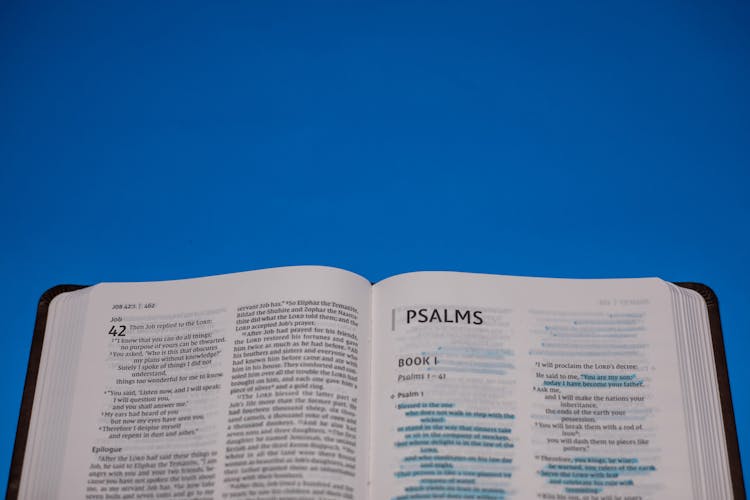 Close-Up Shot Of An Open Bible On A Blue Surface