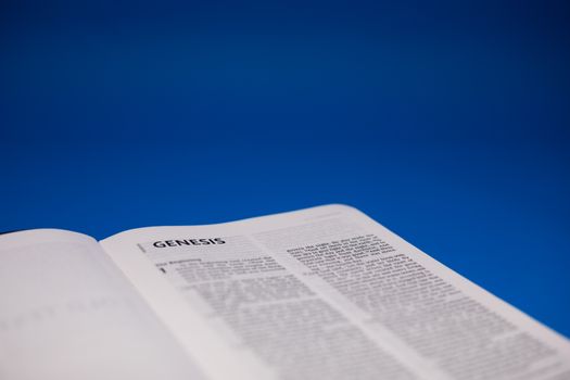 Close-Up Shot of an Open Bible on a Blue Surface