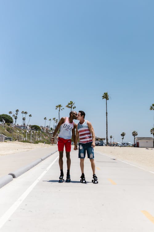 Free Man Kissing Another Man While Roller Skating Stock Photo