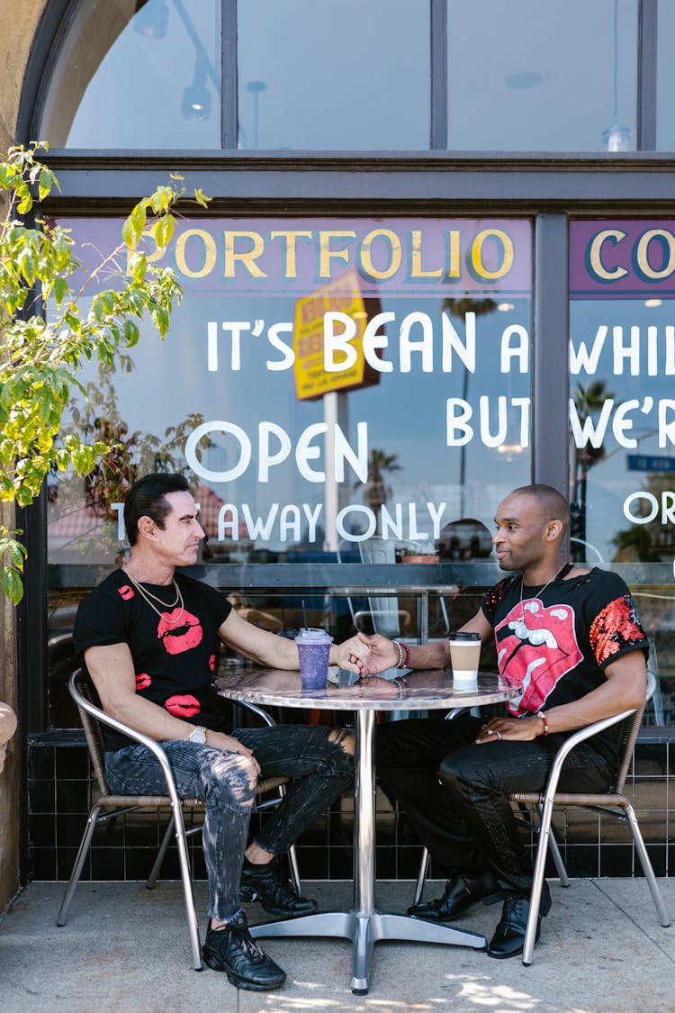 A Couple Holding Their Hands While Sitting Outside The Cafe