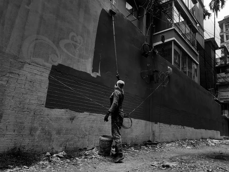 Grayscale Photo Of A Person Painting A Wall