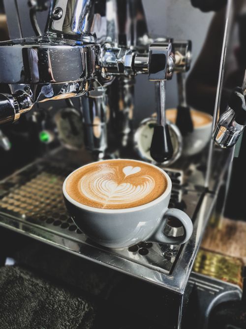 Free Close-up of a steaming cappuccino with latte art on a coffee machine. Stock Photo