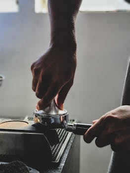 Close-up of a barista using a coffee tamper to press grounds for espresso.