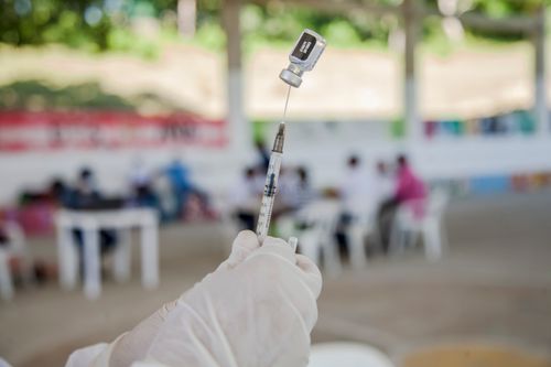 Free A medical professional prepares a syringe for vaccination in an outdoor clinic setting. Stock Photo