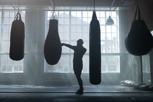 Silhouette training among heavy bags — photo by Ron Lach on Pexels