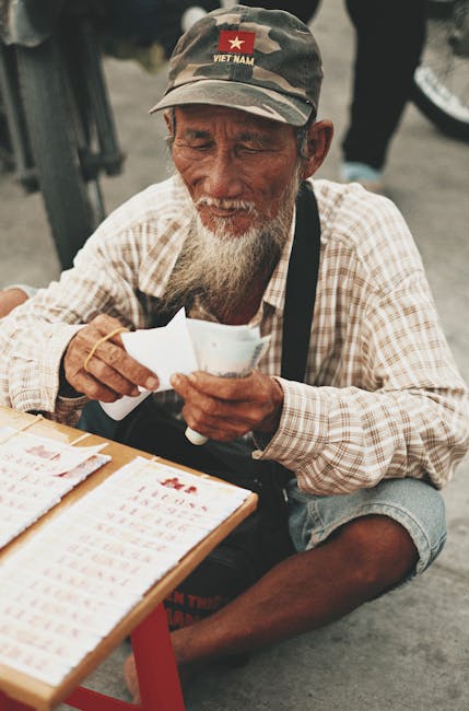 Senior man in Vietnam sitting and counting paper tickets during the day.